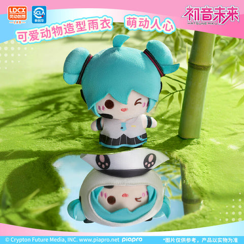 Showcase of Hatsune Miku plush without the hood, alongside a panda-style raincoat version. Her turquoise twin tails and headset remain iconic, while the removable outfit highlights transformation play. Set near bamboo reflections, this detail shot emphasizes customization and cute collectible versatility.