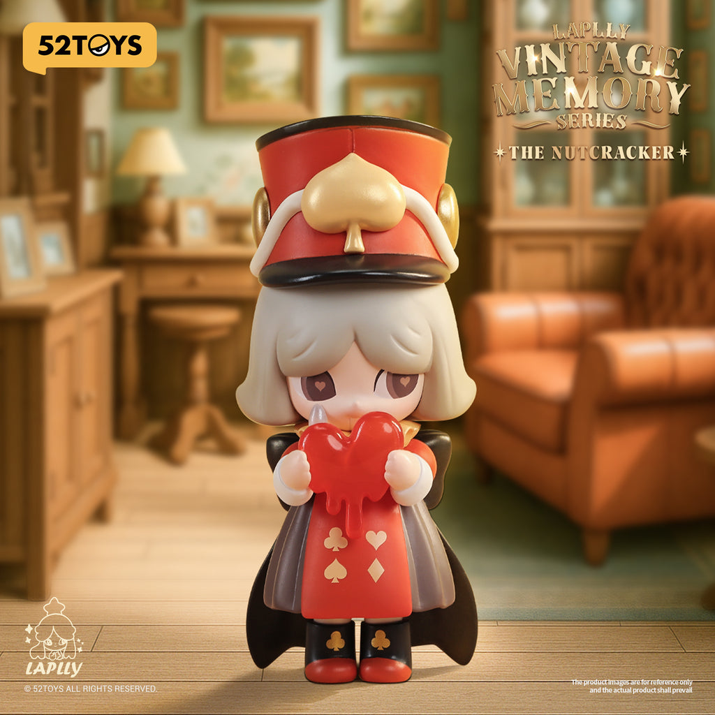 A Nutcracker-inspired figure with a tall red and black soldier’s hat and matching uniform, holding a broken red heart. Her design blends whimsical melancholy with a vintage fairytale aura.