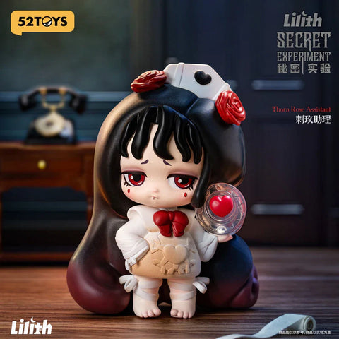 A detailed figure from the 52TOYS "Lilith Secret Experiment" blind box series, titled "Thorn Rose Assistant." The character has sad red eyes, black hair with bangs, and wears a dark hood adorned with red roses and a nurse cap. She’s dressed in a white shirt with a red bow and a beige apron featuring a heart and gear emblem. Holding a clear disc with a red heart inside, she stands in a warmly lit room with a vintage rotary phone in the background, adding to the eerie yet charming vibe.