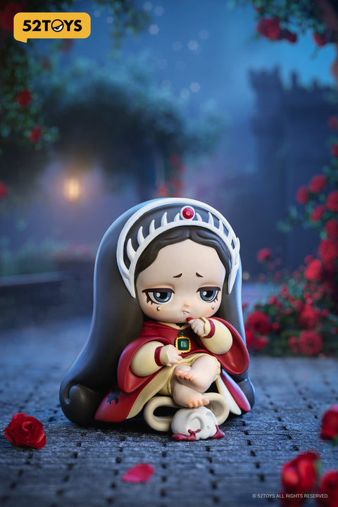 Close-up of the “Devil’s Bargain” figure from 52TOYS’ Lilith: The Century of Mary series. The character sits barefoot with a sorrowful expression, wearing a red cloak and ornate white crown. She clutches a green jewel near her mouth, and a small white skull with bloodstains rests beneath her feet. The scene is set on cobblestones with scattered red rose petals.