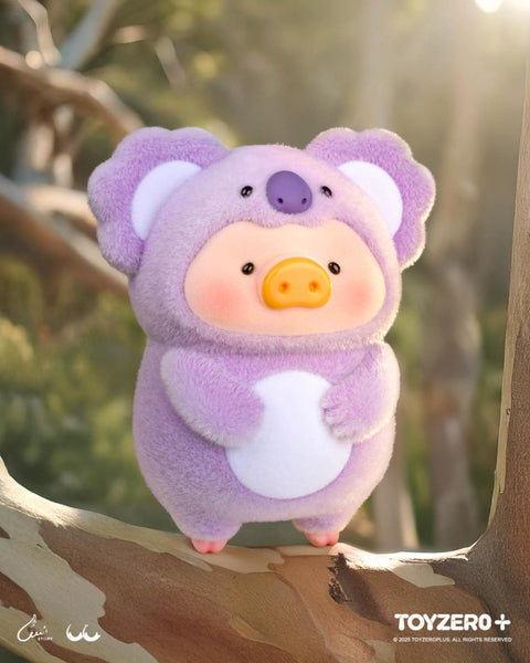 A LuLu the Piggy figure in a fluffy purple koala suit with large round ears, a white belly, and a small koala face detail on top of its head. The background features tall trees and soft forest light.