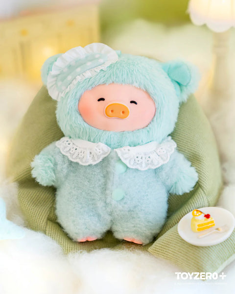A mint-colored plush pig sits on a cushioned surface, dressed in a fuzzy bear suit with rounded ears, lace collar, and mint buttons. A polka-dot sleep cap rests on one ear. A small plate beside it holds a slice of cake. Its closed-eye smile and soft surroundings emphasize an eat-well, cozy nighttime mood.