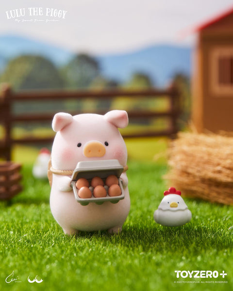 A flocked LuLu piggy holding a carton of brown eggs with a small white chicken standing by its feet.