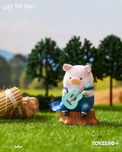 A flocked pink LuLu piggy wearing denim overalls and playing a tiny teal guitar while sitting on a tree stump.