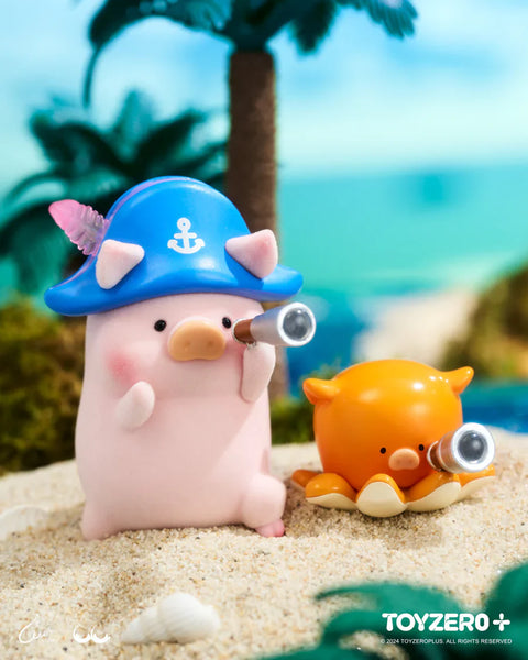 A LuLu the Piggy figure from the Ocean Series by 52TOYS and ToyZero+ stands on sandy beach terrain wearing a blue captain’s hat with an anchor symbol and a pink shell detail. The pig holds a telescope, peering into the distance alongside an orange octopus companion who also holds a tiny telescope. With palm trees and a turquoise ocean in the background, the scene captures a whimsical seafaring adventure vibe.
