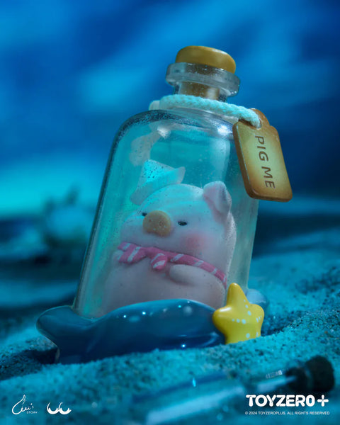 A secret chaser figure from the LuLu The Piggy Ocean Series by 52TOYS and ToyZero+ features LuLu enclosed in a clear message bottle labeled “PIG ME.” The pig wears a tiny blue hat and pink-striped ribbon, peacefully curled up inside, as if adrift at sea. The bottle rests on a blue whale-shaped base with a yellow star, set on a sandy ocean floor. The dreamy underwater ambiance adds a whimsical, treasure-like charm to this special edition figure.