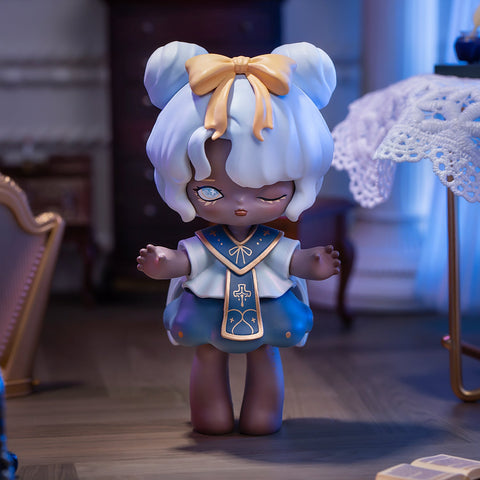 A 3D-rendered MISYA Incredible Mansion Series figure stands in a vintage-style room with warm, dim lighting. The character has dark skin, white twin-bun hair adorned with a golden bow, and heterochromatic eyes—one shimmering silver and the other winking playfully. Dressed in a blue and white outfit with gold trim and cross details, she exudes a charming yet mysterious aura. Ornate furniture, lace tablecloths, and soft shadows enhance the gothic, whimsical atmosphere around her.