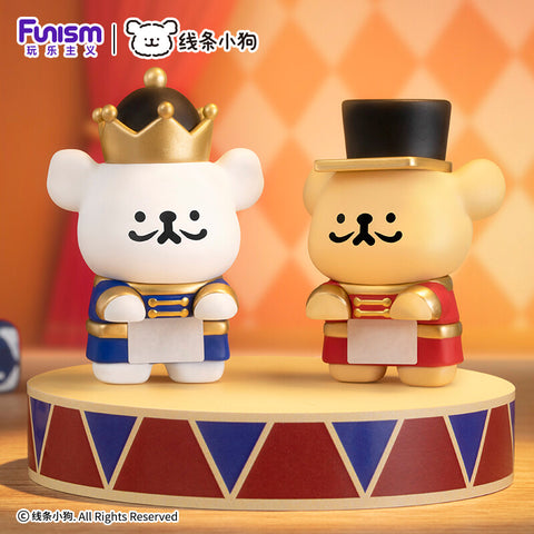 A white pup in a royal crown and blue uniform next to a golden pup in a black top hat and red nutcracker suit.