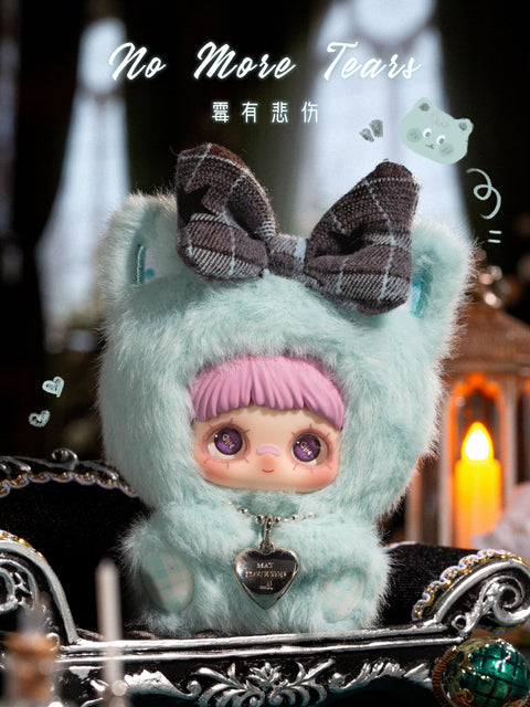 A plush figure sits inside an ornate black tray wearing a mint green fuzzy hood with rounded ears and a dark plaid bow on top. The character has lavender bangs, large purple eyes, and a silver heart pendant necklace. The scene is set against a dark interior with candles, reflective surfaces, and decorative metallic accents, creating a moody yet soft atmosphere.