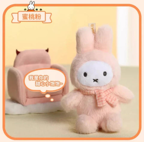 A light pink plush bunny styled in a macaron-themed fuzzy costume with upright ears and rounded limbs. The character has a white face, black eyes, and an X-shaped mouth, paired with a pink knitted scarf that adds warmth and a sweet, pastel aesthetic.