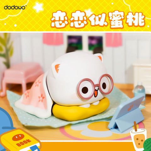 White cat Mitao wears glasses and a blanket, lying on a pillow while happily watching a blue tablet, set in a cozy bedroom.