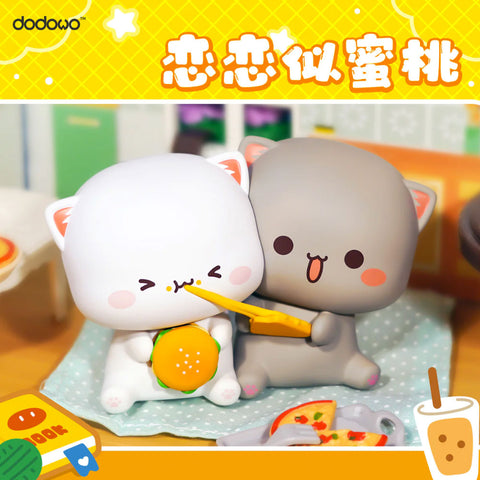 White and gray cats sit together, one holding a burger while being fed pizza by the other, surrounded by pizza slices in a cute dining scene.