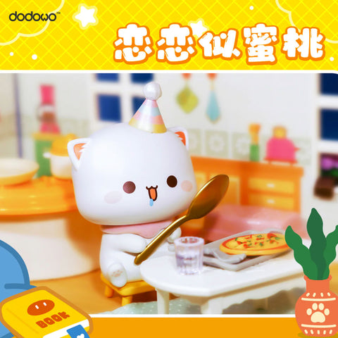 White cat Mitao wears a pastel party hat and sits at a table with pizza, holding a large golden spoon, ready to eat with excitement.