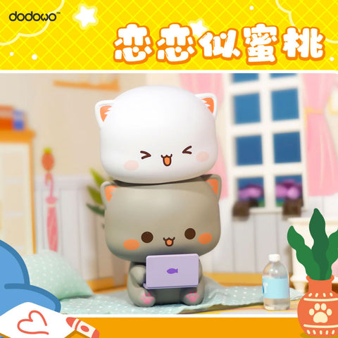 White cat sits atop gray cat, both smiling as they play together with a purple laptop, inside a colorful bedroom with a water bottle on the floor.
