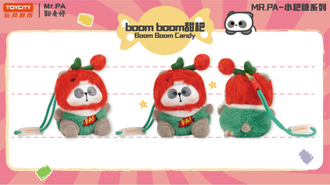 A plush figure of Mr. PA dressed as Boom Boom Candy, wearing a fuzzy red hood with a green outfit and “PA!” written across the chest. The character has a round body, plush arms, and a detachable strap for carrying.