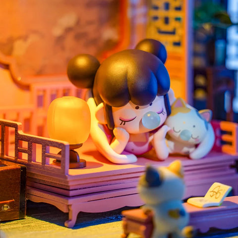 A cozy collectible figurine from the "Nanci Blooming Girl" series features a girl with twin buns lounging on a traditional wooden bed, illuminated by a warm lantern glow. She blows a bubblegum bubble while whispering to her cat companion, who mirrors her playful expression. Another cat sits nearby, adding to the intimate and peaceful nighttime setting. The soft lighting and intricate furnishings create a nostalgic and heartwarming atmosphere, capturing a quiet moment before bedtime.