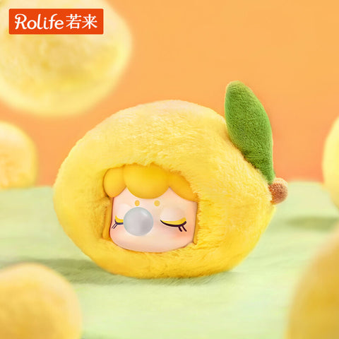 A Nanci Fruit Mood plush styled as a lemon, its round fuzzy body bright yellow with a green felt leaf. The doll’s sweet face peeks out, eyes closed in rest, cheeks blushed, and a bubblegum bubble emerging from its lips. The citrusy theme radiates softness and playful charm.