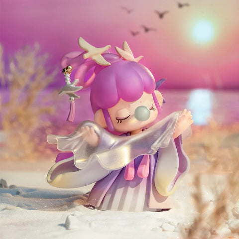 Nanci draped in a flowing purple gradient robe. She is also in front of a sunset.