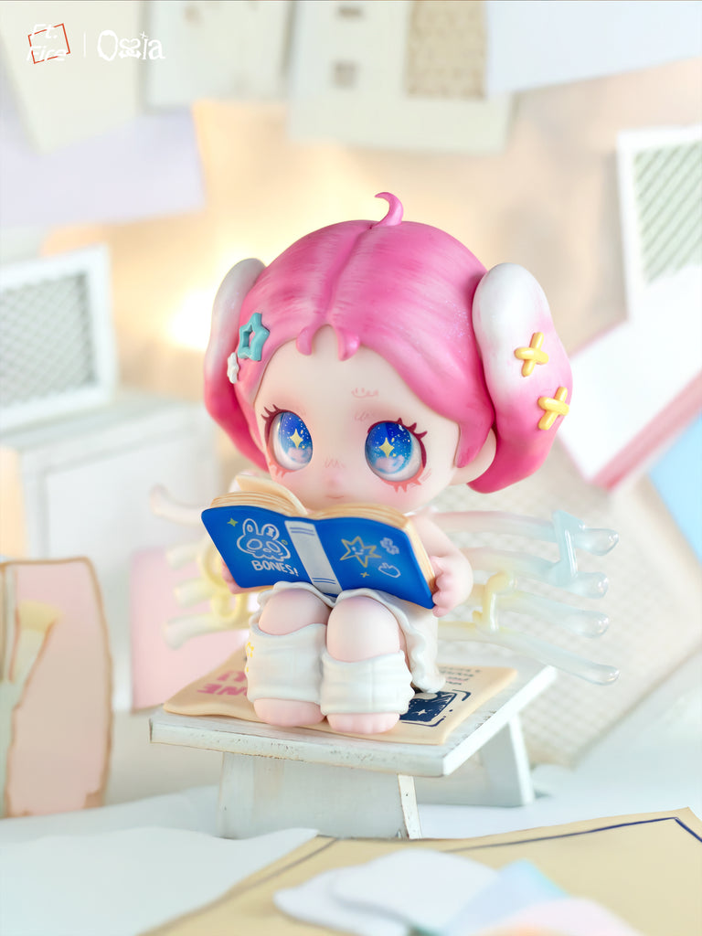 A chibi figure with golden hair and small horns holds a clear staff with a pink heart gem. The character wears a white outfit with metallic wings and sits among glowing yellow moon props and clouds in a soft light setting.