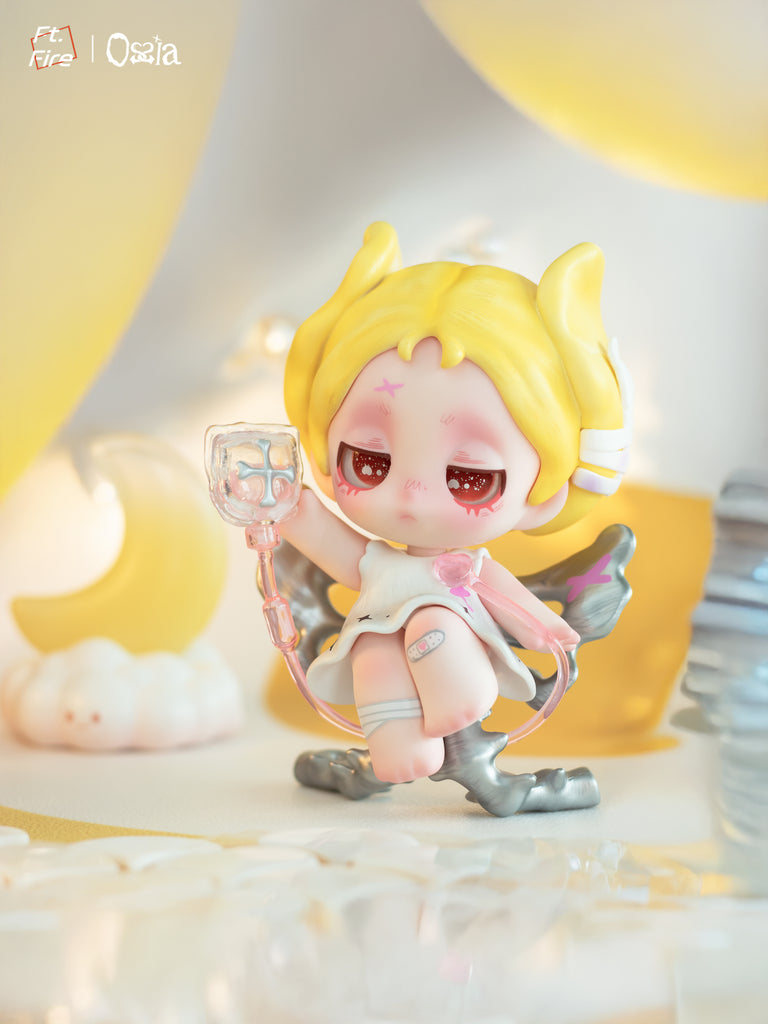 A small figure with red hair and red eyes dressed in black sits on a crescent stand. Red wings and skull motifs accent the design, and soft lighting reflects off the glossy outfit. Red apples and candlelight frame the figure in the background.