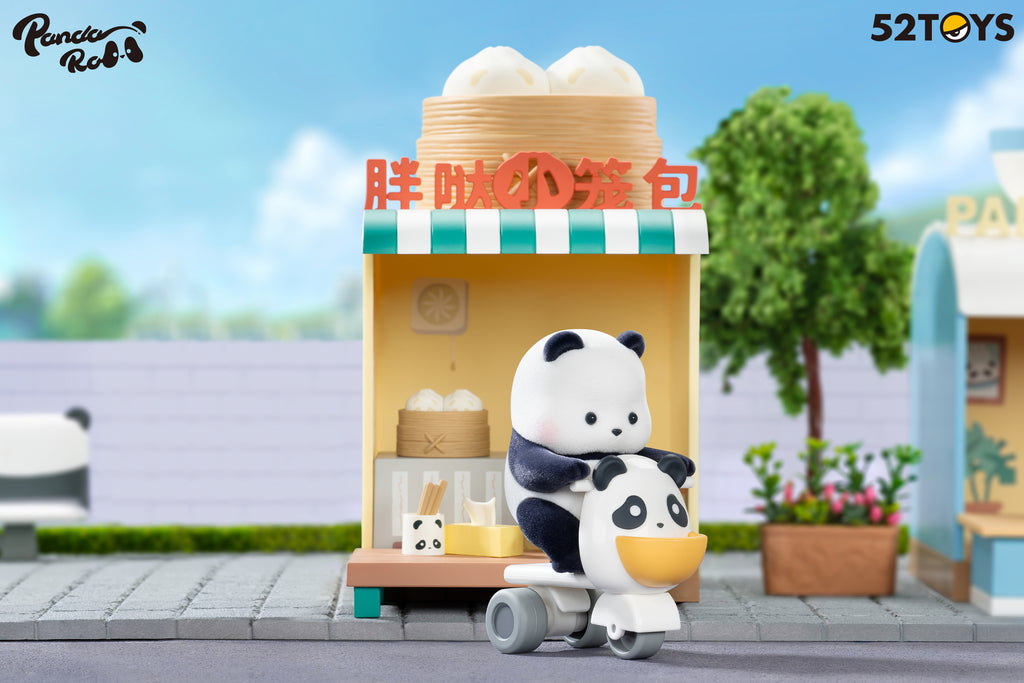 A panda figurine from the 52TOYS Panda Roll Shopping Street series rides a scooter shaped like a panda head in front of a yellow steamed bun shop with a green-and-white striped awning. The shop features a bamboo steamer filled with buns, chopsticks in a panda cup, and a tiny food basket on a table. A large bun steamer prop sits on the shop roof with red signage in Chinese characters. A tree and flower planter complete the bright, playful street scene in the background.