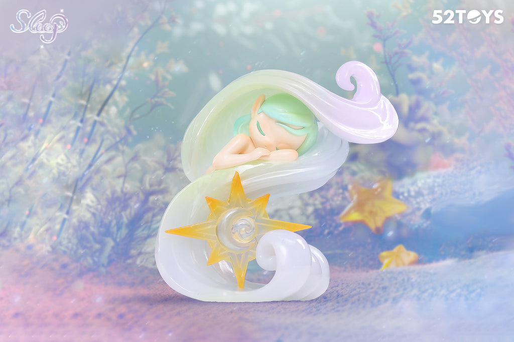 This 52Toys “Sleep: Life of Fantasies” figurine titled “Whispering Breeze” features a peaceful character with mint green hair, resting within a swirl of translucent pastel wind. At the center is a golden sun and crescent moon emblem. The background, filled with sea plants and glowing stars, evokes a dreamy underwater twilight.