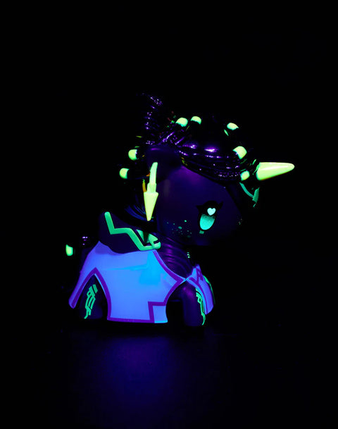 The Mel Unicorno is shown under blacklight illumination, revealing glowing gold, lavender, and UV-reactive highlights along the mane, armor motifs, and decorative markings. Chrome textures reflect cool ultraviolet tones, emphasizing the sculpted details and elegant silhouette under the enhanced lighting.