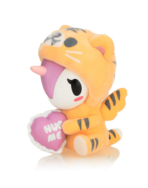 Huggy in an orange and black striped tiger onesie, clutching a pink heart-shaped pillow that reads "Hug Me."
