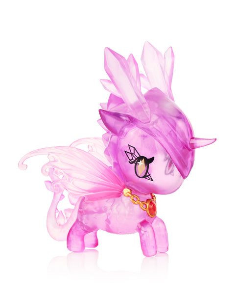 This image shows the Tokidoki Unicorno Mystical Dragon “Crystal Energy Dragon,” a translucent purple figure with faceted crystal shapes on its head, clear sculpted wings, and a red gemstone pendant on a gold chain. Its body has a scaled texture and is photographed on a white background.