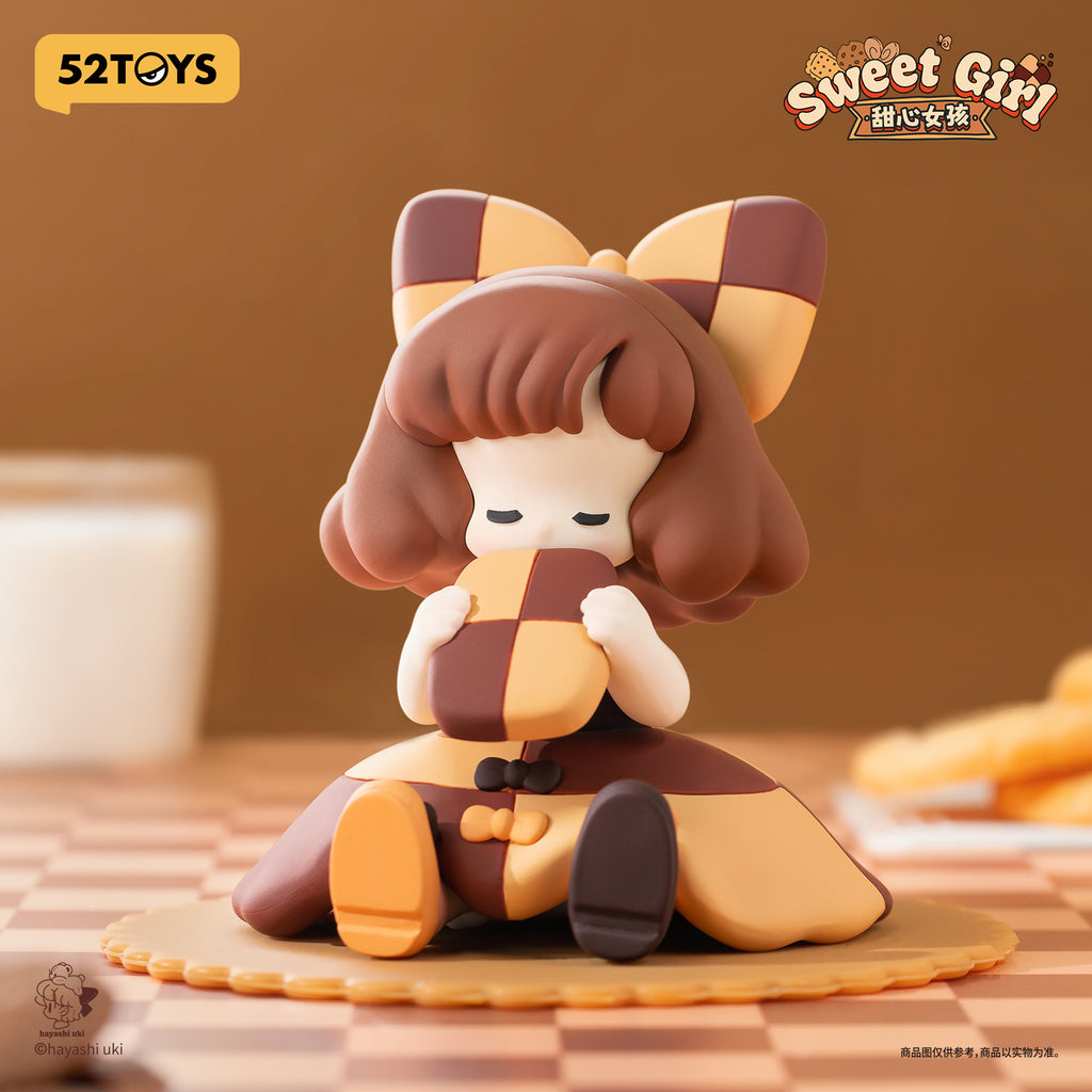 A charming figurine girl with brown curled hair and a giant checkered bow. She clutches a mosaic square cookie patterned in golden yellow and chocolate brown, sitting serenely with eyes closed.