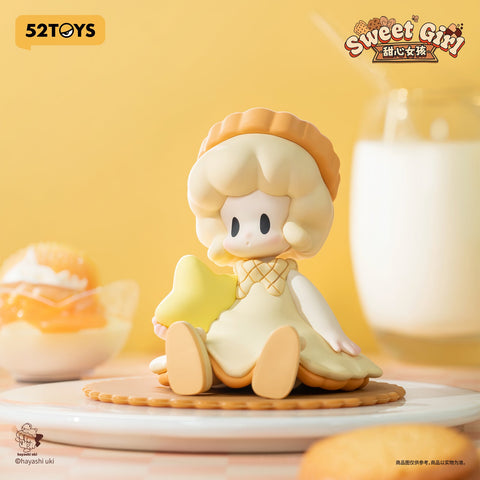 A doll-like girl with short blonde hair and a beret, dressed in a cream and caramel outfit. She sits on a round cookie plate, holding a bright yellow star-shaped biscuit.
