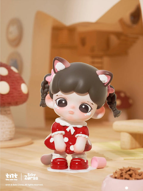 A seated cat figure with black hair and glossy ears wears a pink apron dress with white paw prints. The character frowns tearfully beside pastel food cans on a beige rug, lit by sunlight streaming through a softly blurred background.