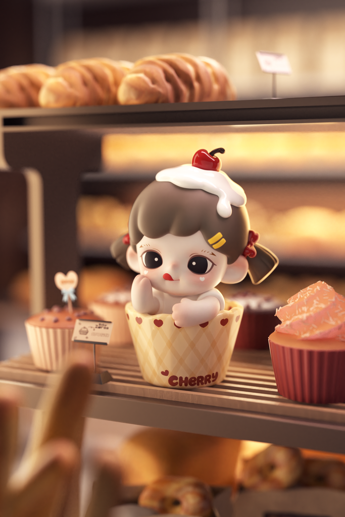 A cute figurine of a girl peeks out from a yellow checkered cupcake wrapper labeled “Cherry.” She has brown hair tied with red ribbons, whipped cream and a cherry on top of her head, and red heart prints on the cup. She’s surrounded by pastries and cupcakes in a bakery display.