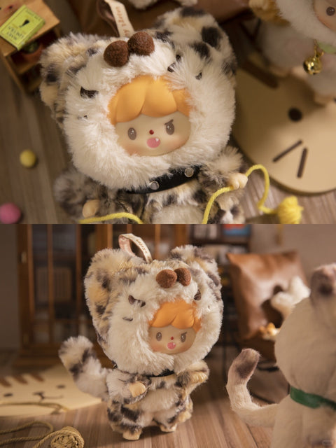Two close-up shots of the Cool Leopard Cat plush from the Finding Unicorn x 卓大王 “My Little Cat Series” blind box collection. The doll has a cheeky expression with small fangs, orange hair, and wears a soft, spotted leopard-print costume with rounded ears and a fluffy tail. It features a black collar with silver studs and is shown in a cozy miniature room with cat-themed decor, wooden flooring, yarn, and playful props creating a warm and lively environment.